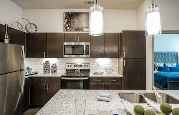 A modern kitchen with a stainless steel refrigerator and a granite countertop.