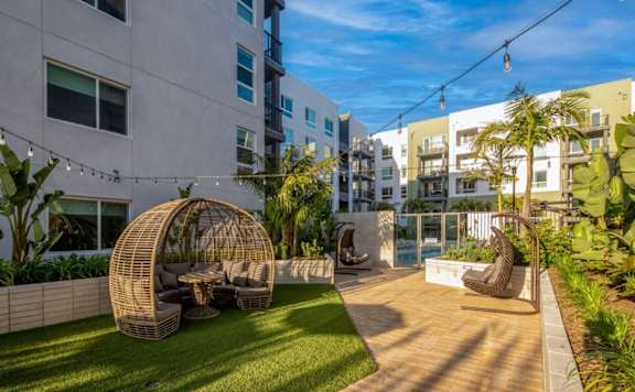 A modern outdoor seating area with a woven structure and a bench.
