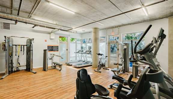A gym with exercise equipment and a cityscape mural on the wall.