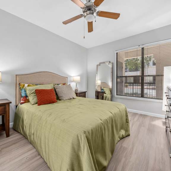 A bedroom with a bed, nightstand, and a ceiling fan.