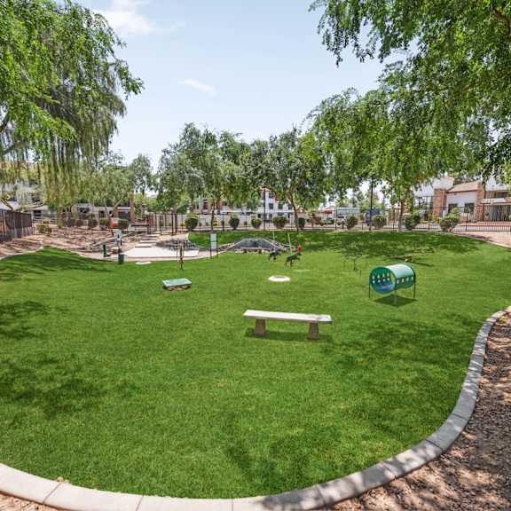 A park with a green lawn and a bench.