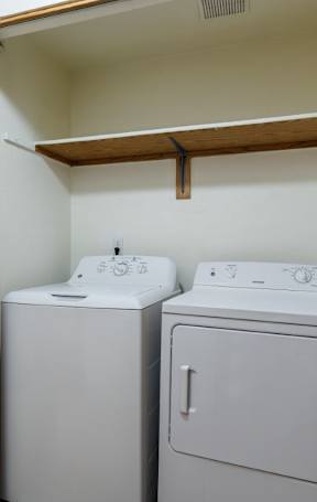 A white toilet sits in a bathroom with wood floors and white walls.