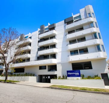 a white apartment building with a blue sign in front of it at The Kenmore Los Feliz, Los Angeles, CA