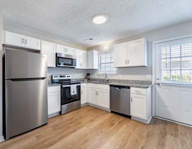 A kitchen with a refrigerator, microwave, oven, and sink.