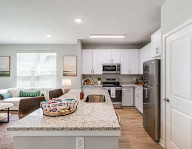 an open kitchen and living room with a granite counter top