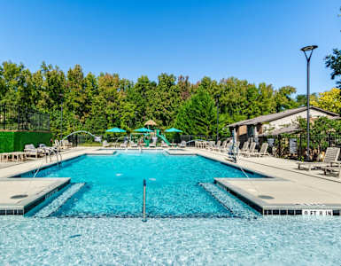 a swimming pool with chairs and umbrellas at the resort on a sunny day