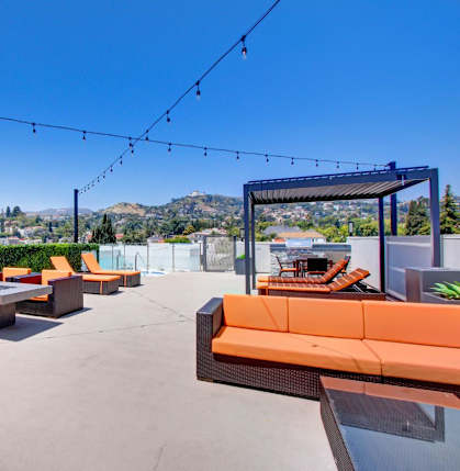 a roof deck with orange couches and a fire pit