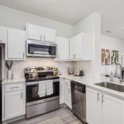 A modern kitchen with white cabinets and stainless steel appliances.