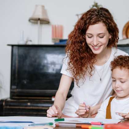 a woman and a child working on a piece of paper