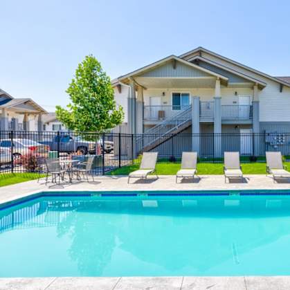 A swimming pool in front of a house with a balcony.