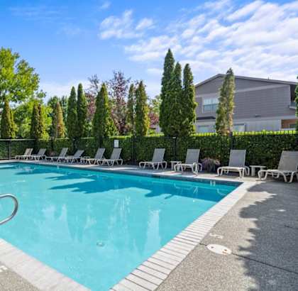 A swimming pool surrounded by trees and lounge chairs.