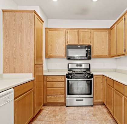 A kitchen with wooden cabinets and a stove top oven.