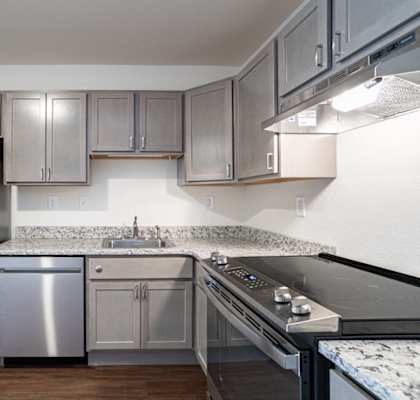 an empty kitchen with stainless steel appliances and granite counter tops