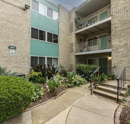 the entrance to an apartment building with stairs and a garden