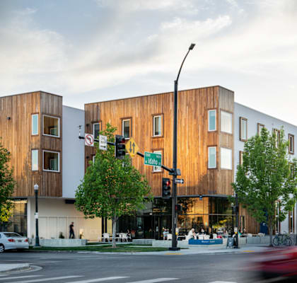 A modern building with wooden panels is situated on a street corner.