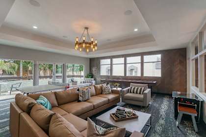 A living room with a brown couch and a chandelier.