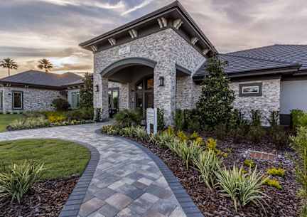 A house with a stone facade and a curved walkway in front.