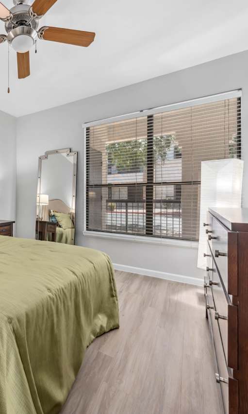 A bedroom with a bed, nightstand, and a ceiling fan.