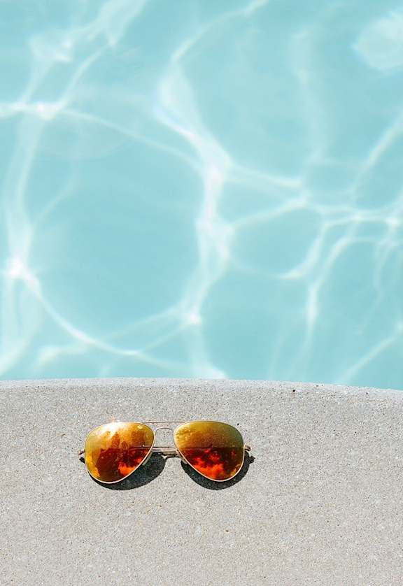 sunglasses on the edge of a swimming pool