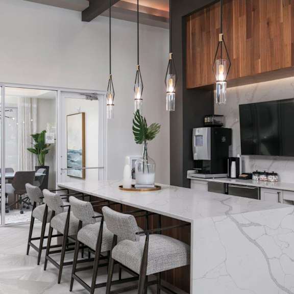A modern kitchen with a long island and chairs.