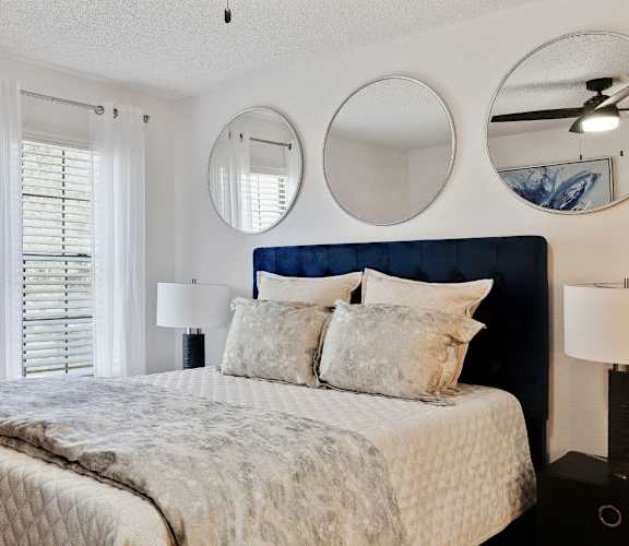 A bedroom with a large bed and three round mirrors on the wall.