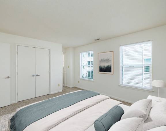 A bedroom with a large bed and a window with blinds.