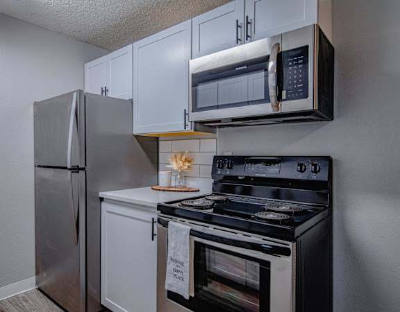 A kitchen with a stainless steel refrigerator, microwave, and oven.