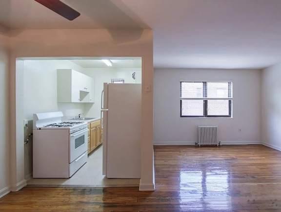 A kitchen with white appliances and wooden floors.