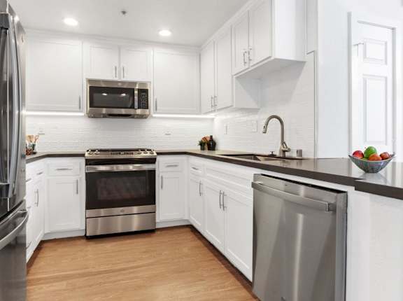 A modern kitchen with white cabinets and stainless steel appliances at Toluca Court, Toluca Lake, California
