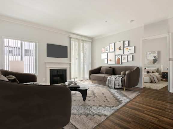 A living room with a brown couch, a fireplace, and a TV on the wall at The Plaza Apartments, Los Angeles
