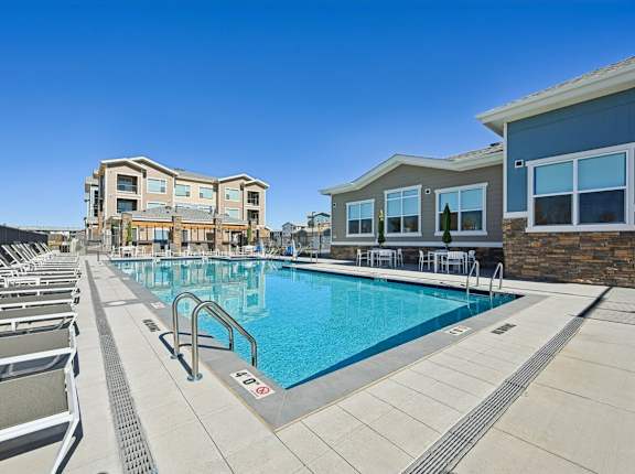 A swimming pool with lounge chairs and a building in the background.