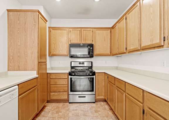 A kitchen with wooden cabinets and a stove top oven.