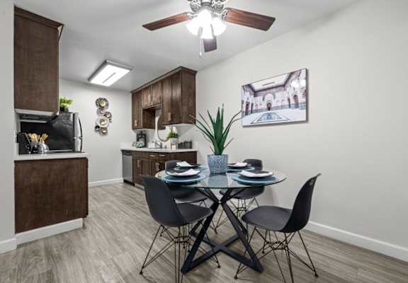A dining room with a table set for two and a ceiling fan.