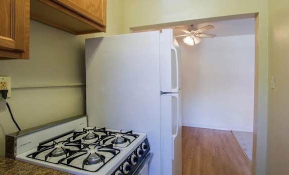 A white refrigerator is in a kitchen with a stove below it.