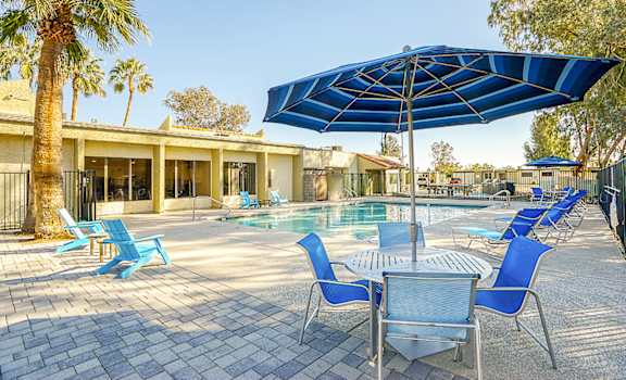A pool area with blue chairs and a blue umbrella.