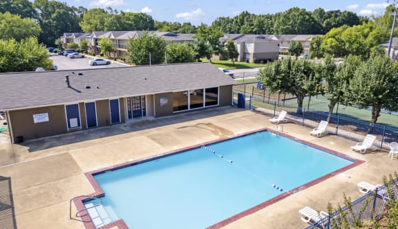 an aerial view of a swimming pool with a building and trees