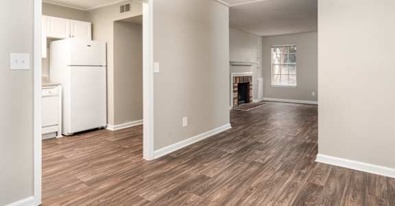 an empty living room and kitchen with a refrigerator and microwave