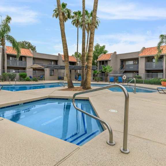 A swimming pool surrounded by palm trees and lounge chairs.
