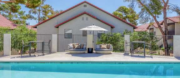 a pool with chairs and an umbrella in front of a house
