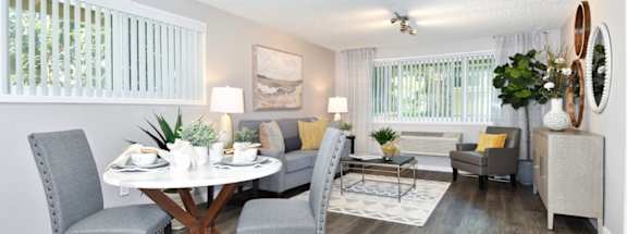 A dining room with a round table and grey chairs.