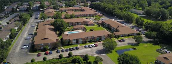 A bird's eye view of a residential complex with a pond in the foreground.