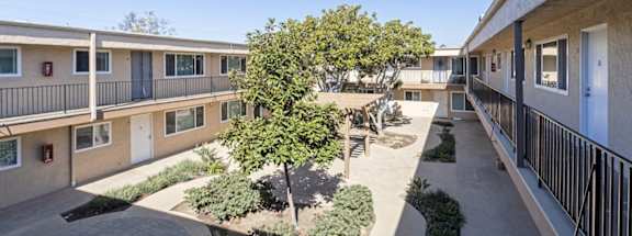 the outlook of the courtyard of an apartment building with trees and bushes