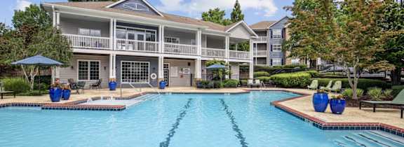 A large swimming pool in front of a multi-story apartment building.