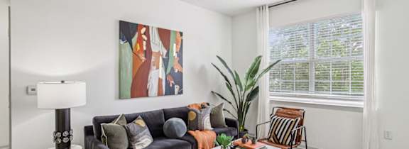 A living room with a black couch, a checkered rug, and a painting on the wall.