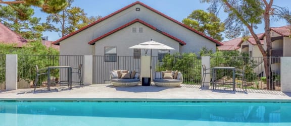 a pool with chairs and an umbrella in front of a house
