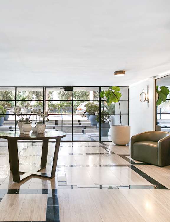 A modern living room with a long sofa, a coffee table, and a large abstract painting on the wall.