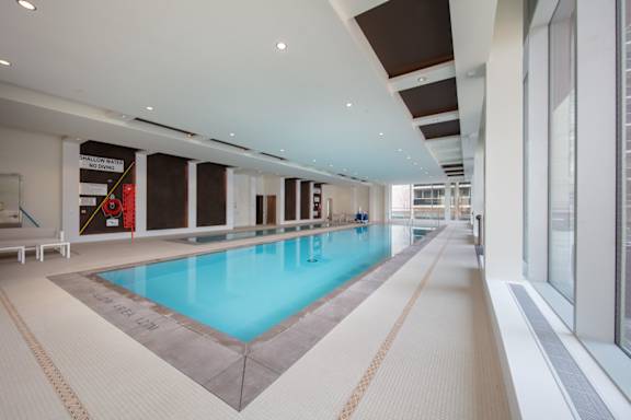 A large indoor swimming pool with a light blue water.