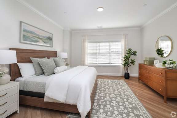 A bedroom with a large bed, a dresser, and a mirror.
