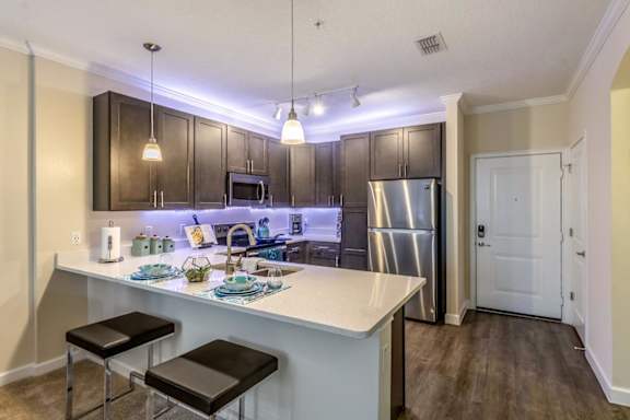 A kitchen with a white counter top and a stainless steel refrigerator.