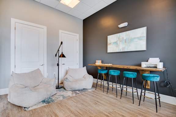 A room with a grey wall and a wooden floor with a white door and a table with four chairs.